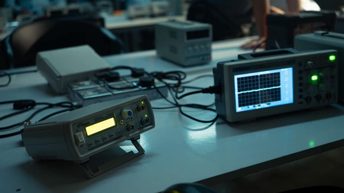 A dimly lit electronics lab featuring oscilloscopes and equipment on desks, creating a technical atmosphere.