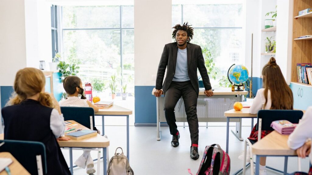 A teacher engages with students in a bright, modern classroom setting, promoting education.