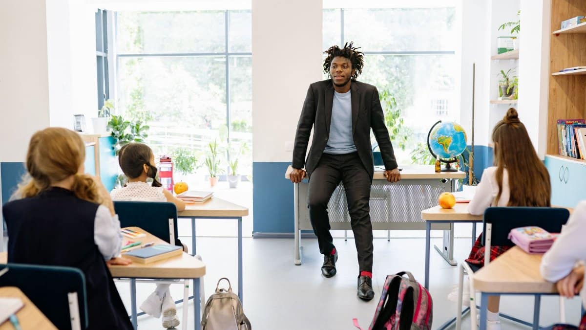 A teacher engages with students in a bright, modern classroom setting, promoting education.