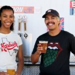 Two friends enjoying craft beer at a brewery, smiles and casual attire enhance the fun atmosphere.
