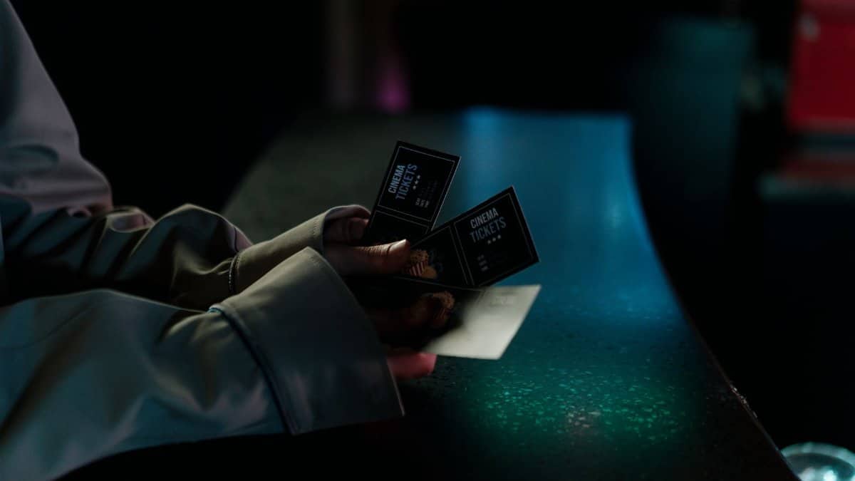 Moody image of a person holding cinema tickets at night, highlighting anticipation of a movie night.