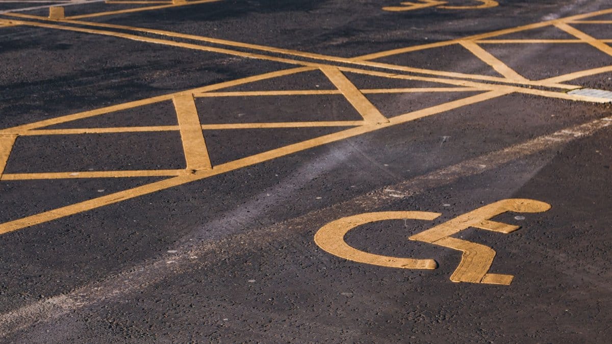 Yellow markings for handicapped parking spot on asphalt pavement.