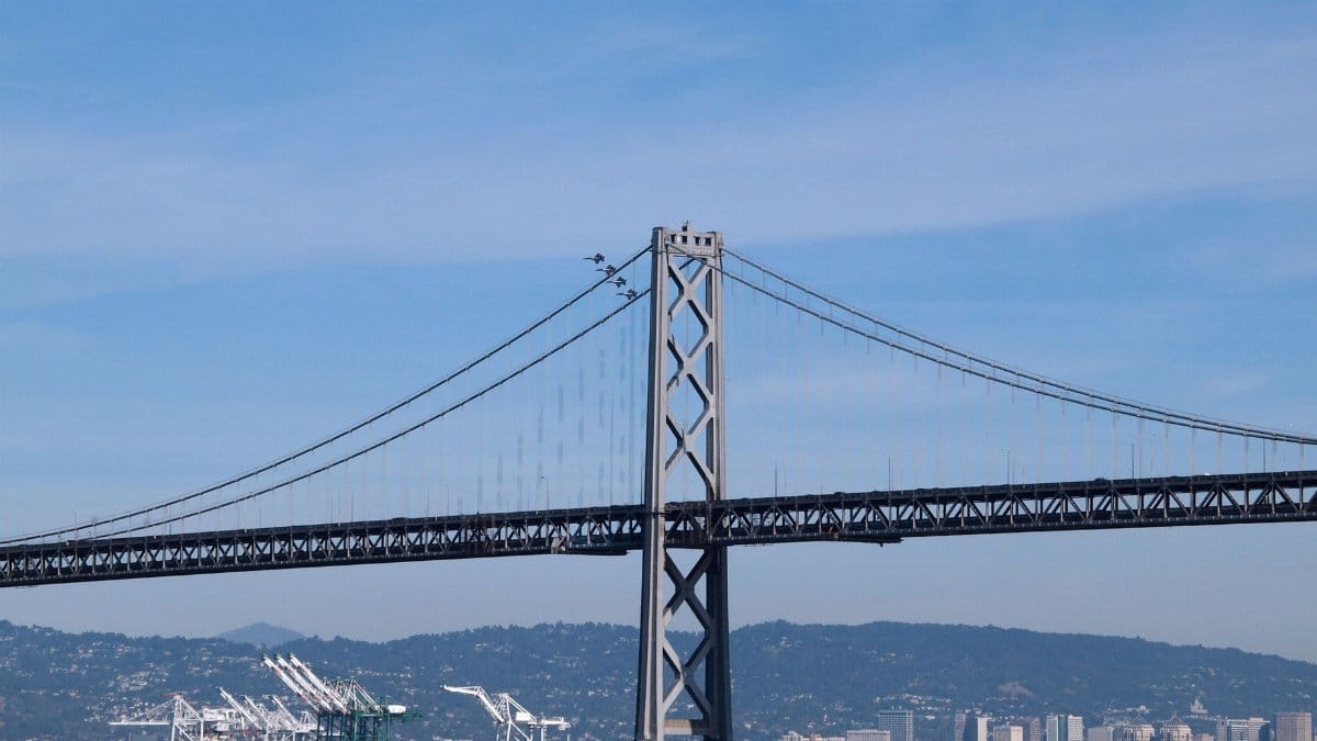 Scenic view of the Bay Bridge with San Francisco cityscape and water in the foreground.