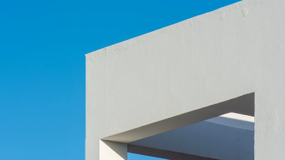Modern architectural structure with sleek white lines against a vibrant blue sky.