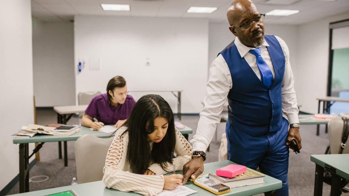 Teacher monitors students during an exam in a classroom, emphasizing academic integrity.