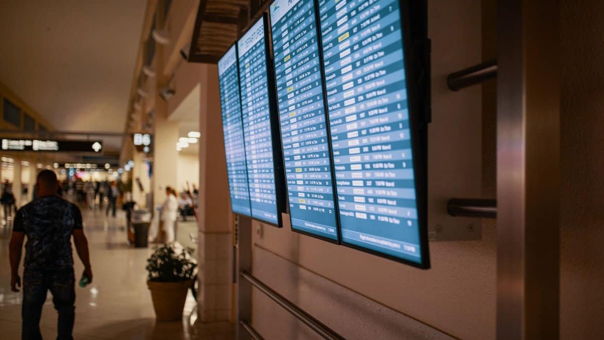 Airport terminal with digital flight information boards showing arrivals and departures.