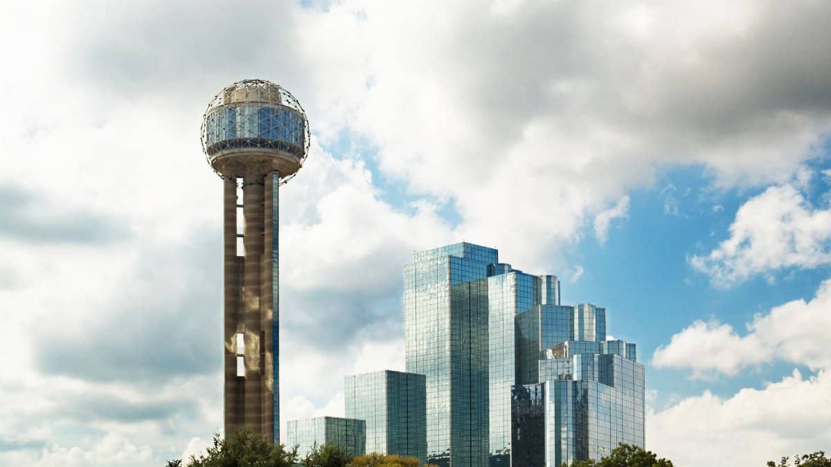Reunion Tower and modern skyscrapers in Dallas, Texas against a cloudy sky.