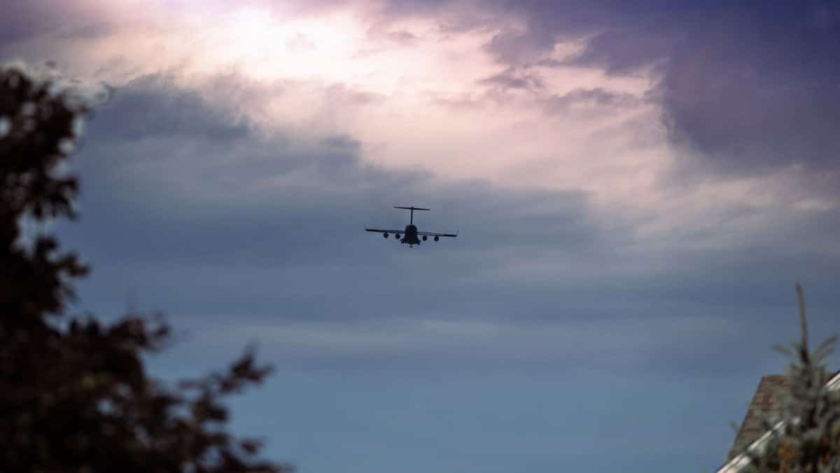 Silhouette of an airplane soaring in a cloudy sky, showcasing aviation and freedom.