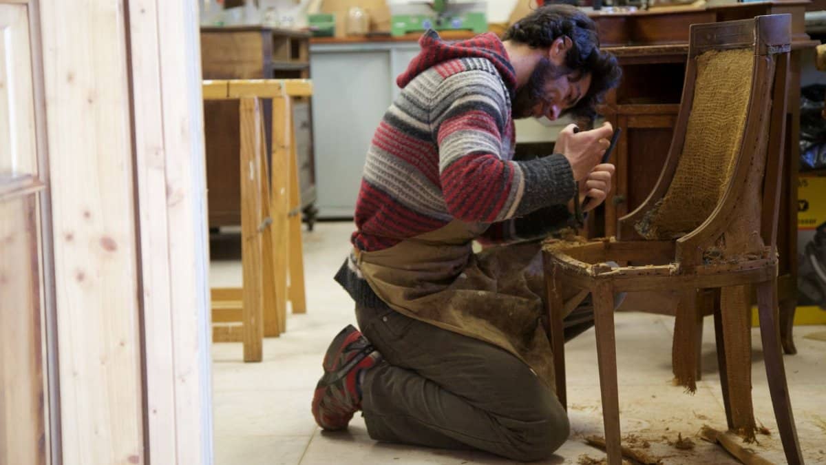 Skilled craftsman restoring an antique wooden chair in a workshop, focused on detailing.