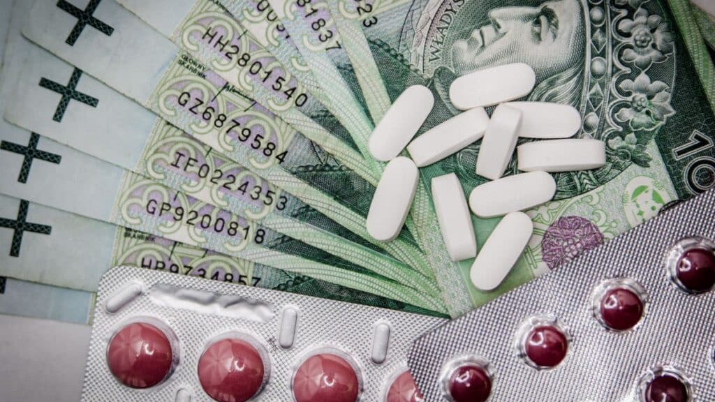 Polish 100 złoty notes with pills and blister packs, illustrating medical costs.
