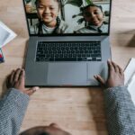 Crop anonymous clever African American female talking with pupils about plan of homework online on laptop