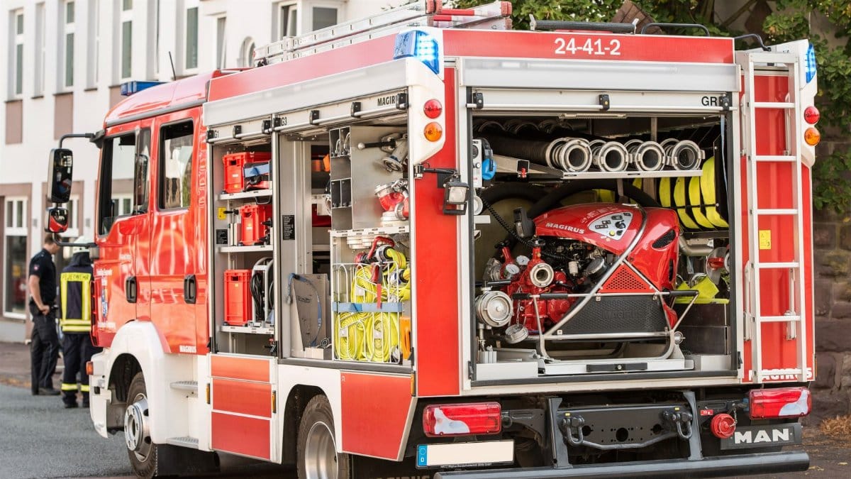 A vibrant red fire truck parked on a city street with equipment visible, showcasing urban emergency readiness.