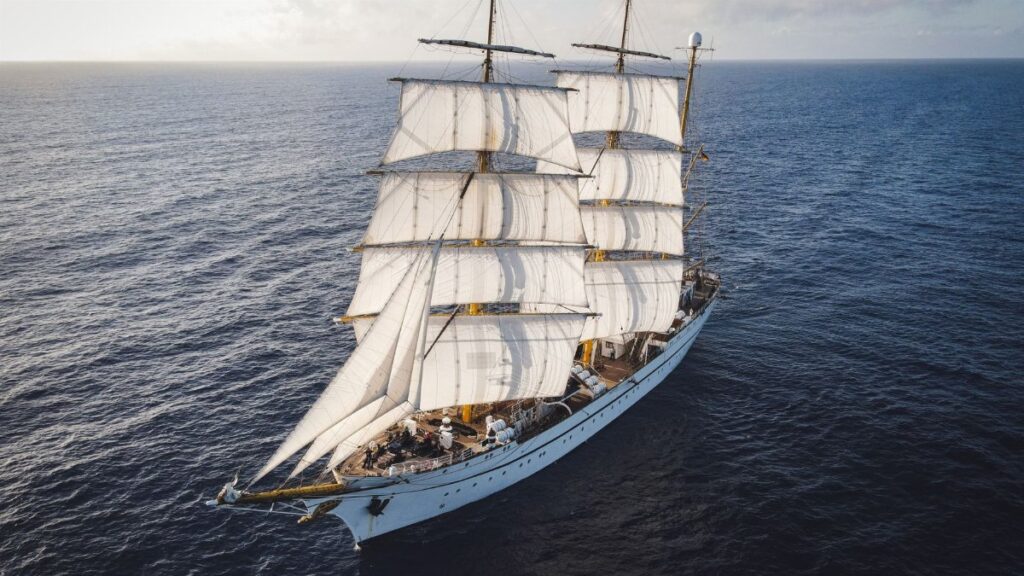 A grand tall ship with full sails navigates across the vast ocean, capturing the spirit of adventure.