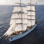 A grand tall ship with full sails navigates across the vast ocean, capturing the spirit of adventure.