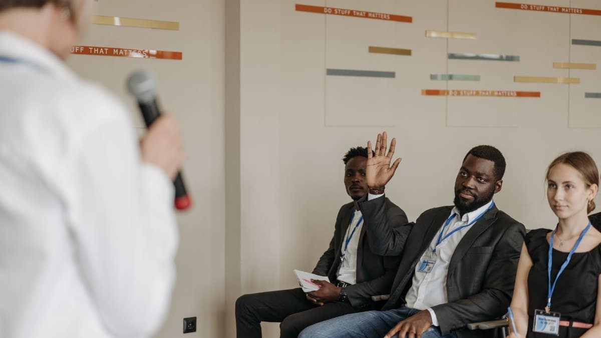 Engaged participants in a business conference, raising questions to the speaker.