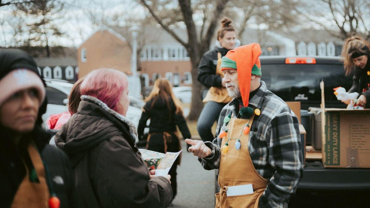 Volunteers hand out gifts during a community Christmas celebration outdoors.