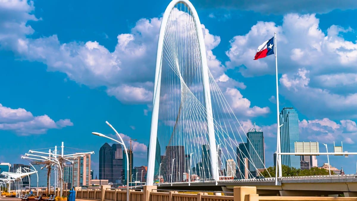 The iconic Margaret Hunt Hill Bridge in Dallas, Texas under a bright blue sky with clouds.
