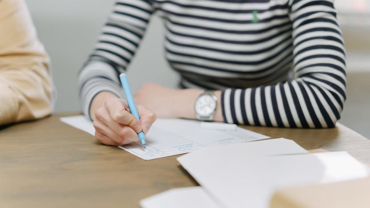 Adult writing with colored pen on documents, emphasizing strategic planning.