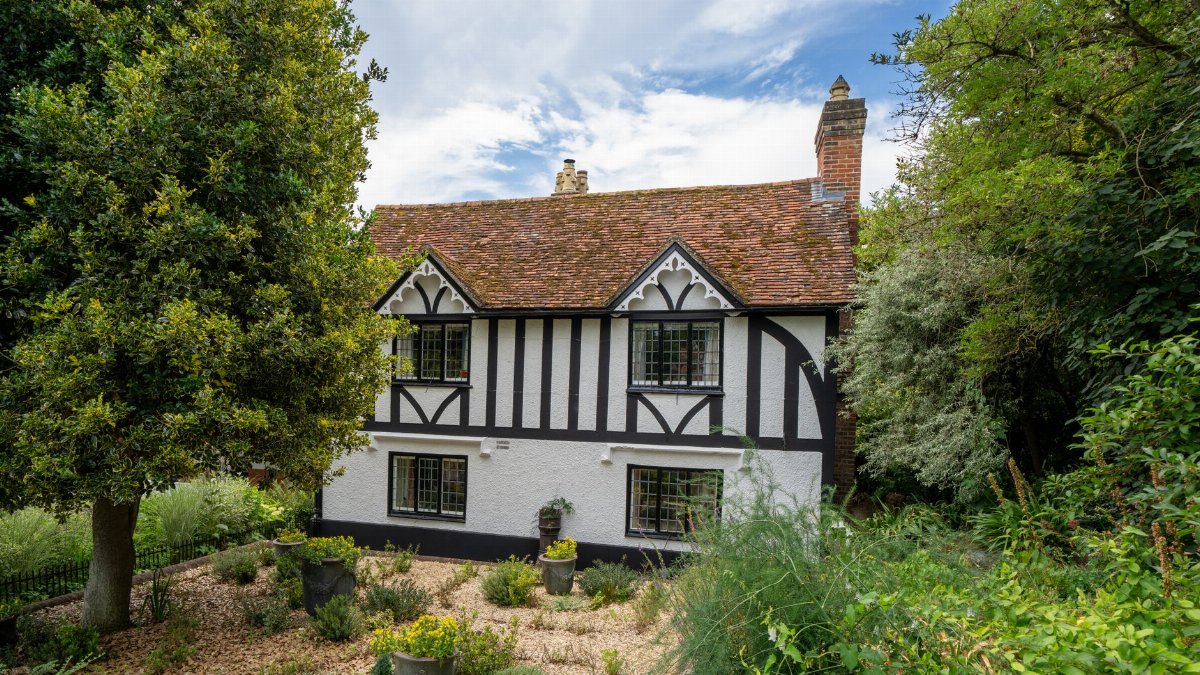 Explore a picturesque Tudor style cottage nestled in the rural village of Latimer, England, surrounded by lush greenery.