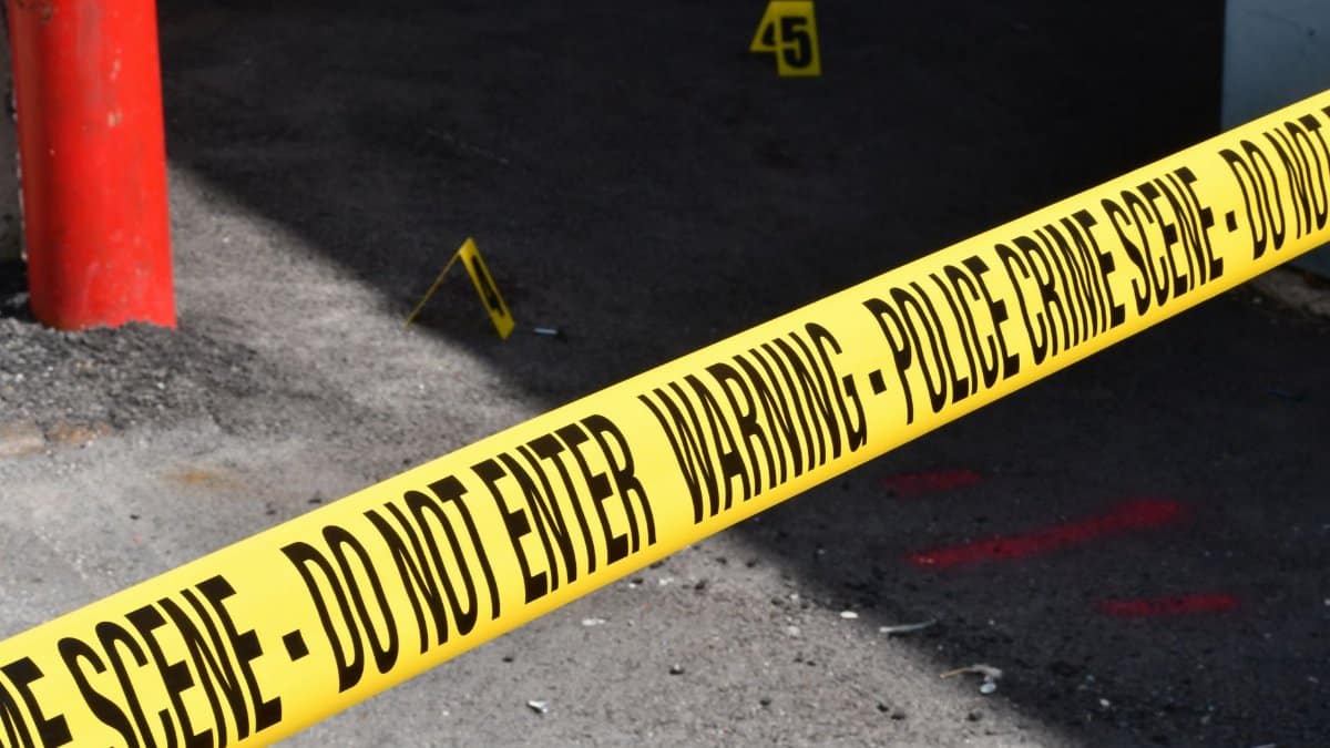 Yellow police crime scene tape marking a restricted urban area on concrete ground.