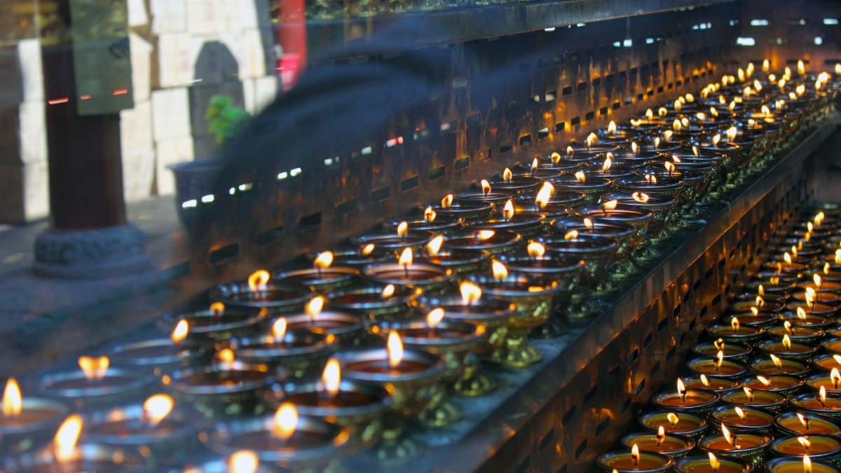 A serene display of lit oil lamps in a Buddhist temple creating a spiritual ambiance.