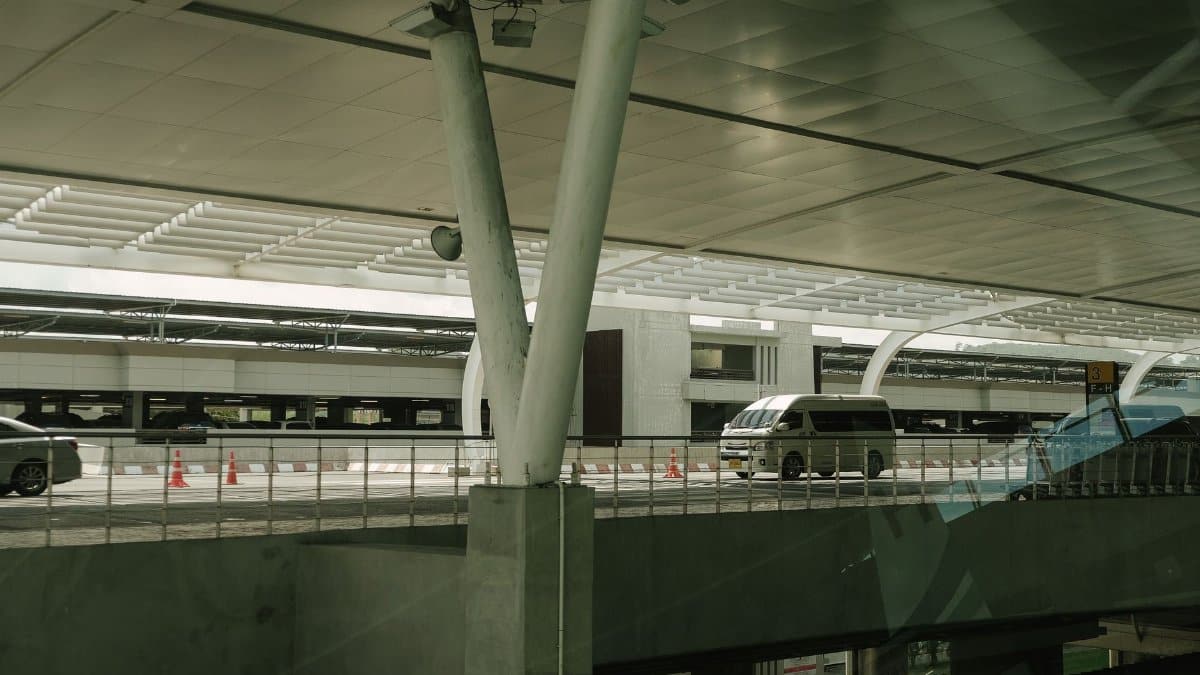 A modern airport departure terminal with vehicles in transportation and architecture focus during the day.