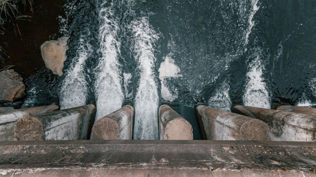 Aerial view of cascading water over a concrete dam showcasing turbulent flow and water management.