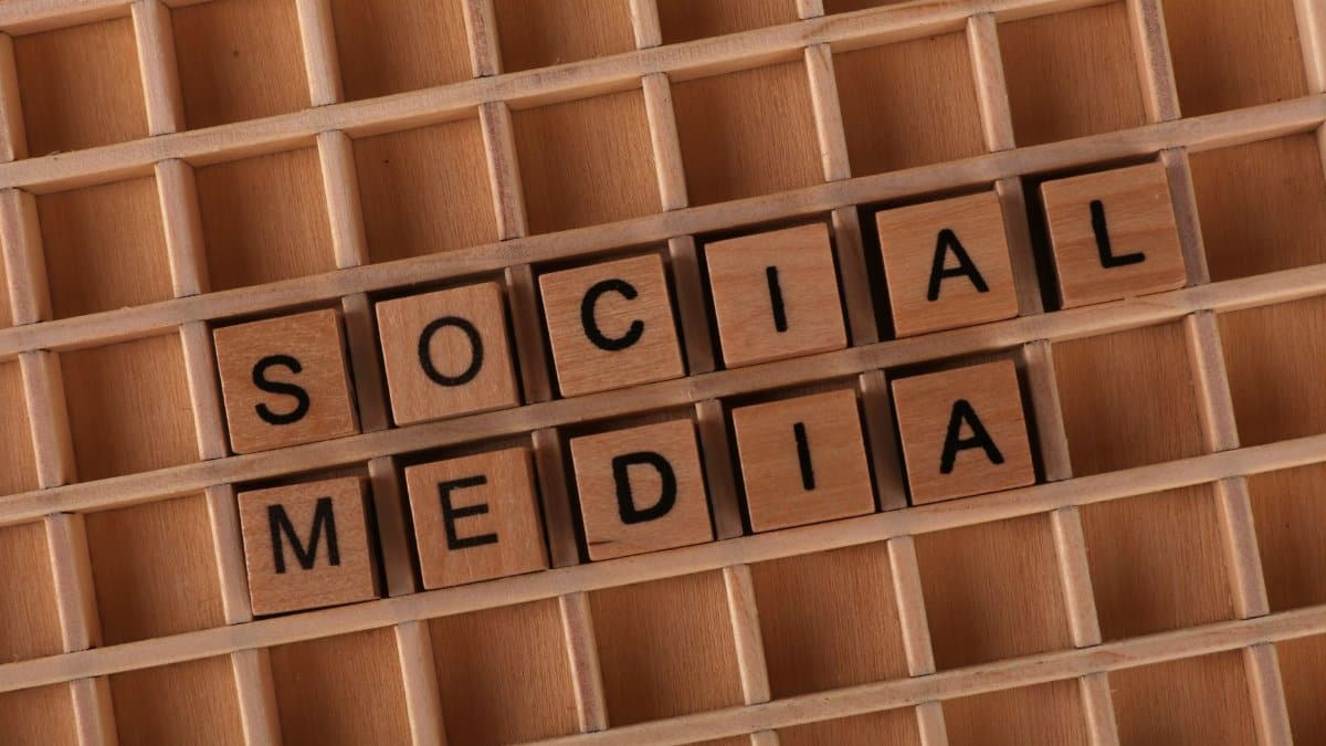 Wooden Scrabble tiles arranged to spell 'Social Media' on a grid background.