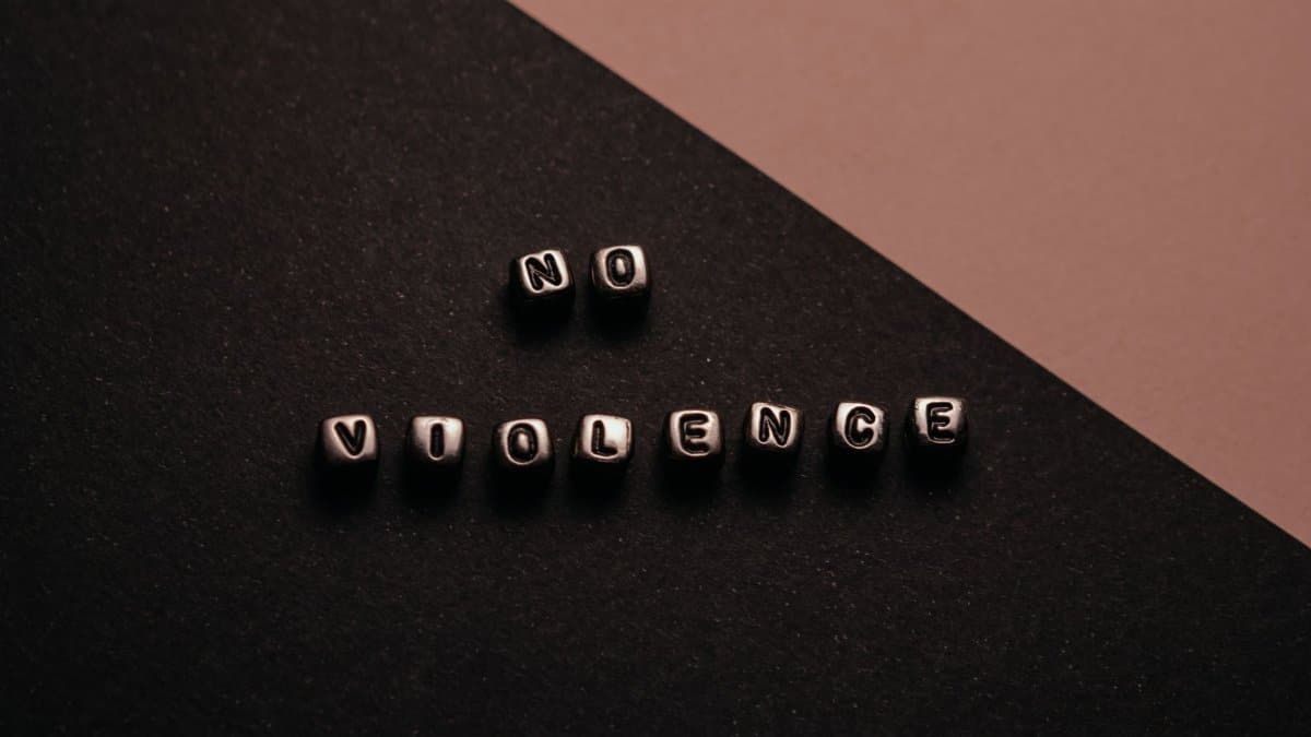 Artistic composition with text cubes spelling 'No Violence' on a two-tone background.