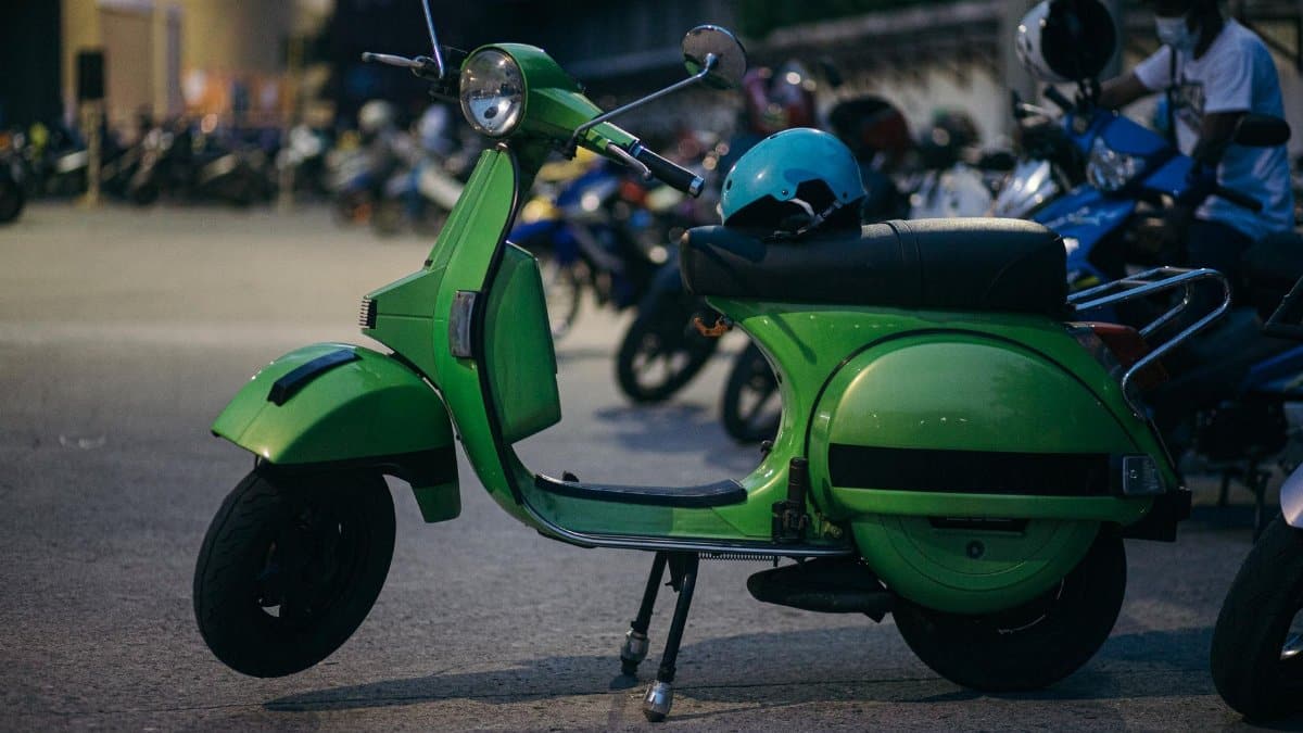 A vivid green scooter parked outdoors with a helmet on the seat.