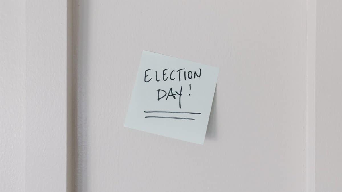 Sticky note with 'Election Day' message on a white wall background.