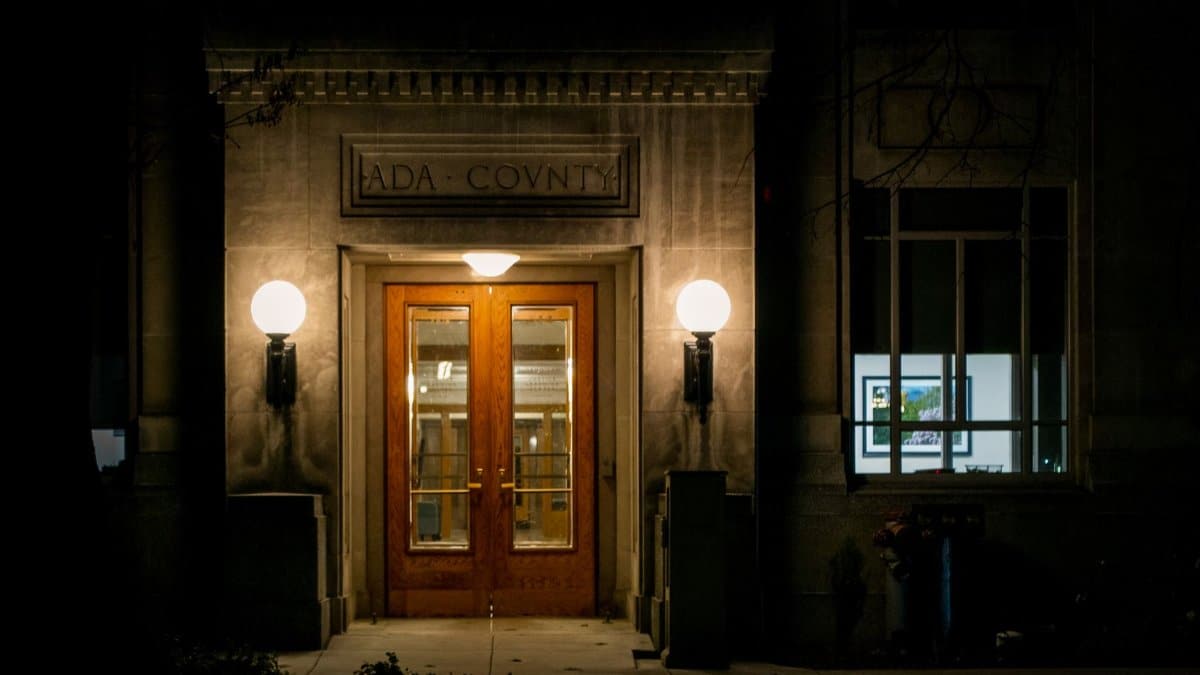 Night view of a wooden door entrance at Ada County building, illuminated by warm lamps.