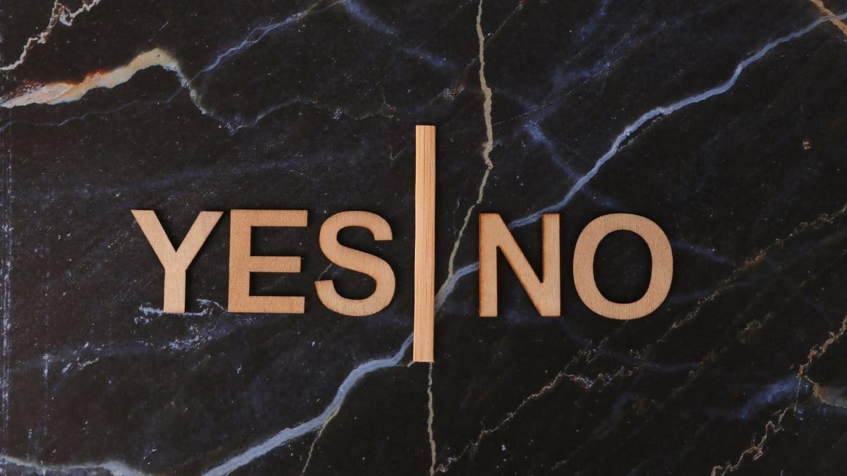 A stylish contrast of wooden letters 'Yes' and 'No' on dark marble background.