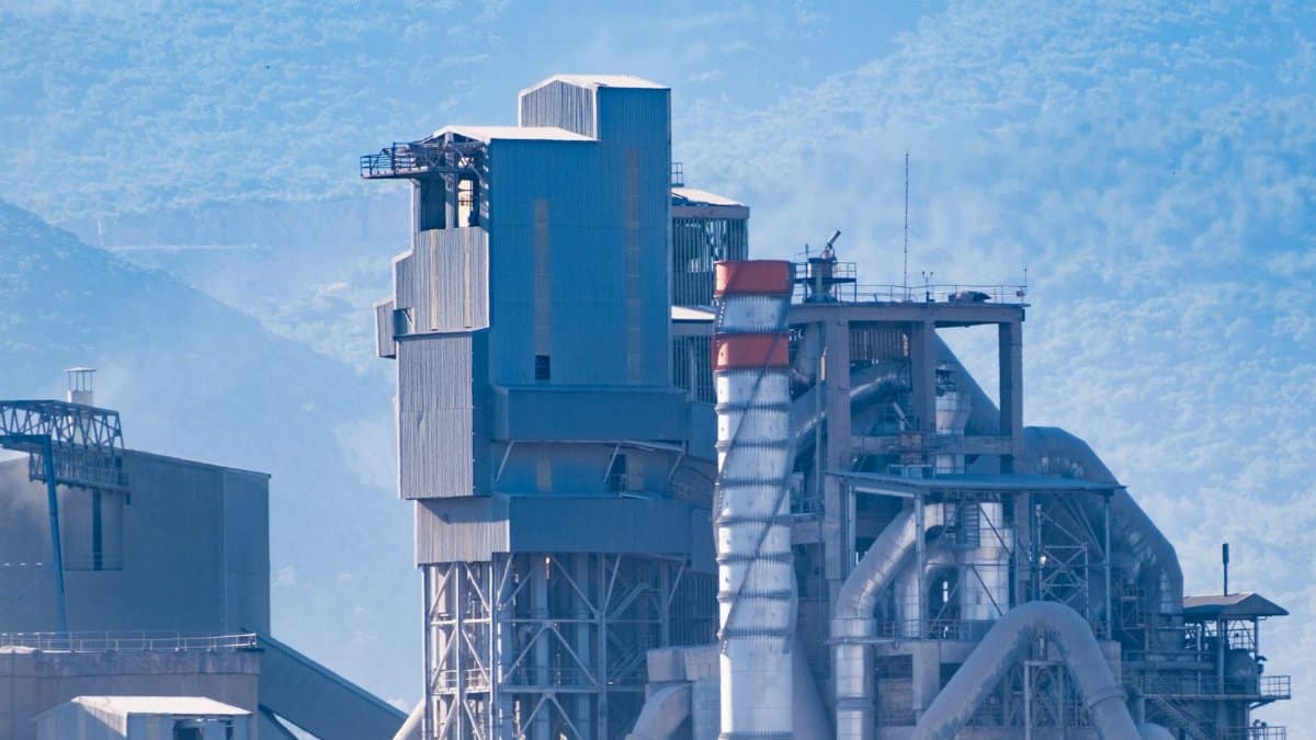 Aerial view of a modern industrial factory with mountains in the background, showcasing advanced architecture.