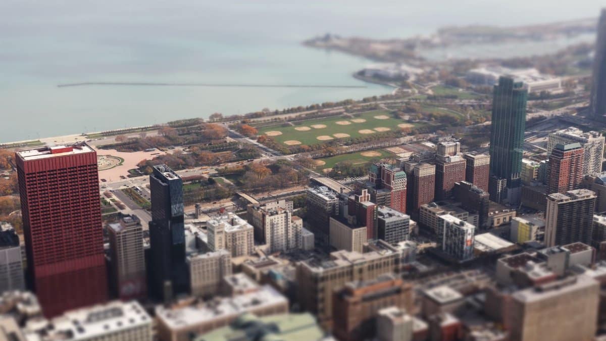 Tilt-shift aerial view of downtown Chicago with Lake Michigan in the background, showcasing skyscrapers and urban landscape.