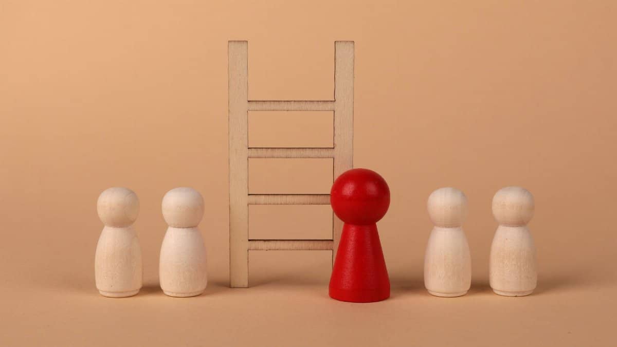 Abstract representation of leadership with wooden figures and ladder on a neutral background.