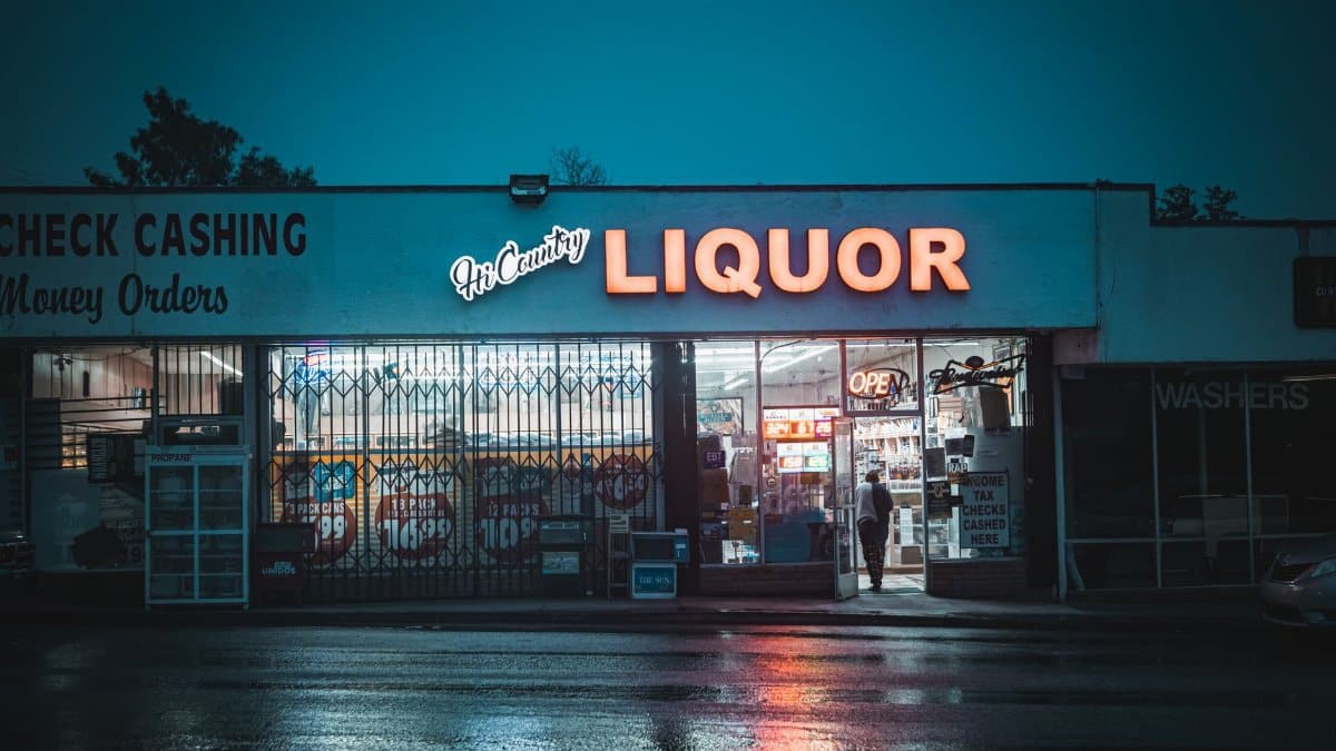 Rainy evening view of a neon-lit liquor store in Yucaipa, CA, United States.