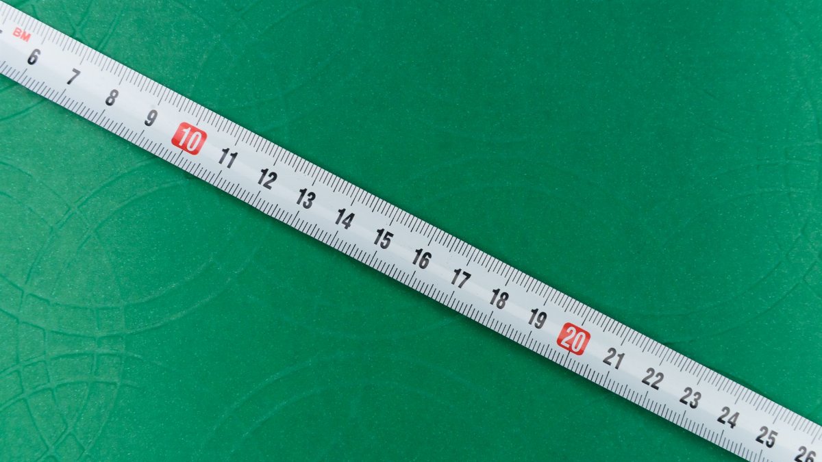 A close-up shot of a tape measure on a textured green background, showing precise measurements.