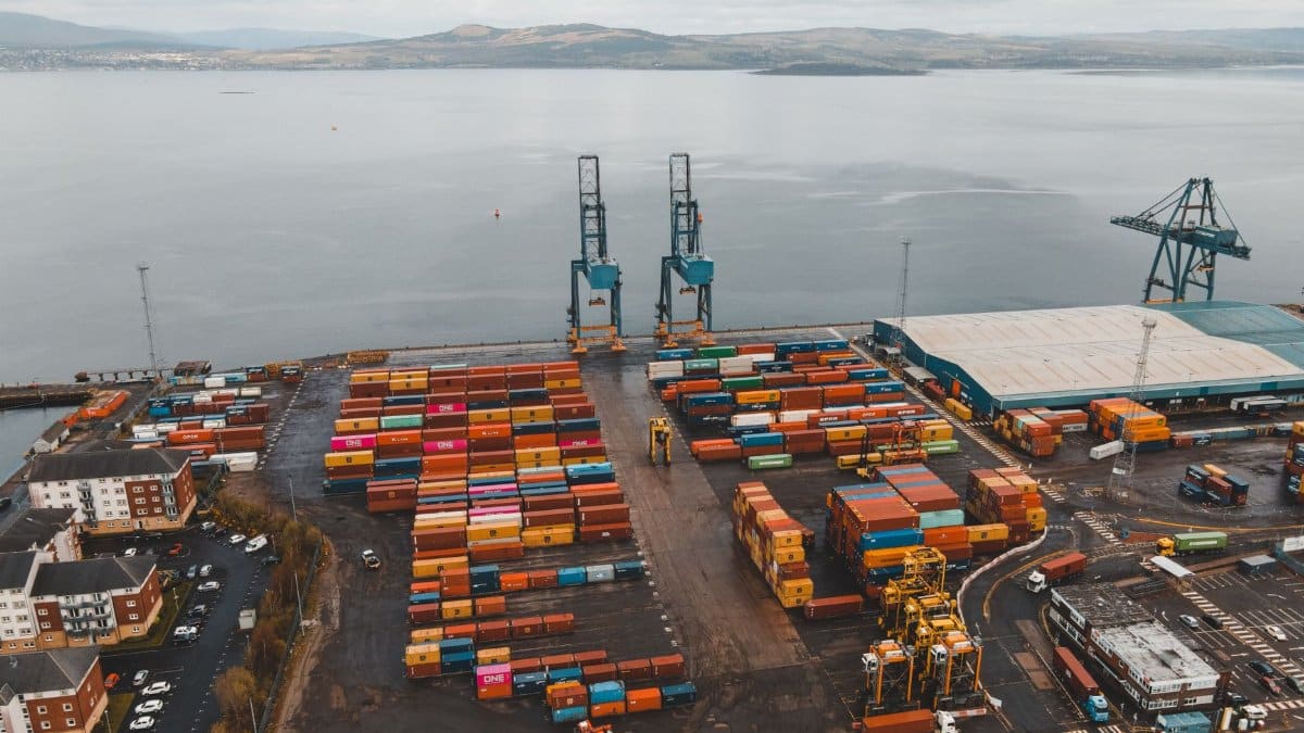 Aerial shot of a busy container port in Scotland with cranes and colorful cargo containers.