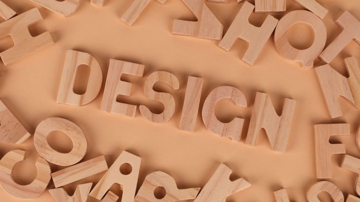 Wooden letters arranged to form the word 'design' on a brown background, top view.