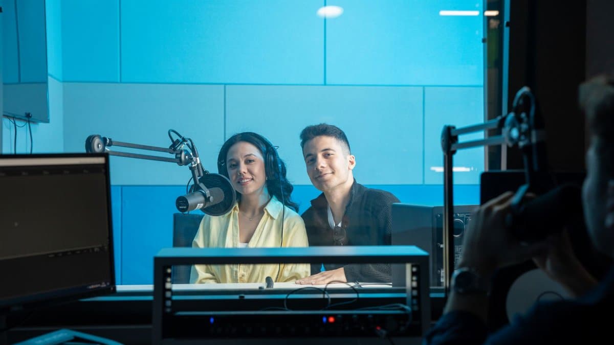 Two people in a radio studio broadcasting a show, featuring professional equipment and microphones with a blue theme.