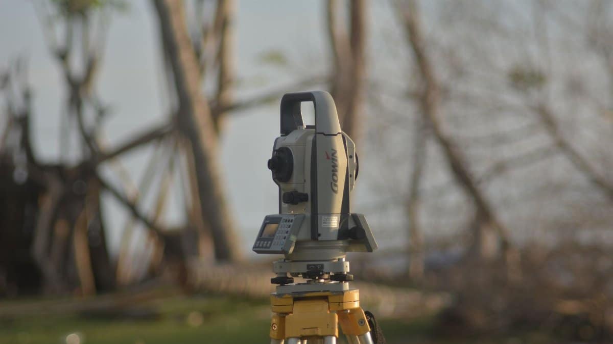 A precise total station used for geodetic surveying at a construction site with a natural background.