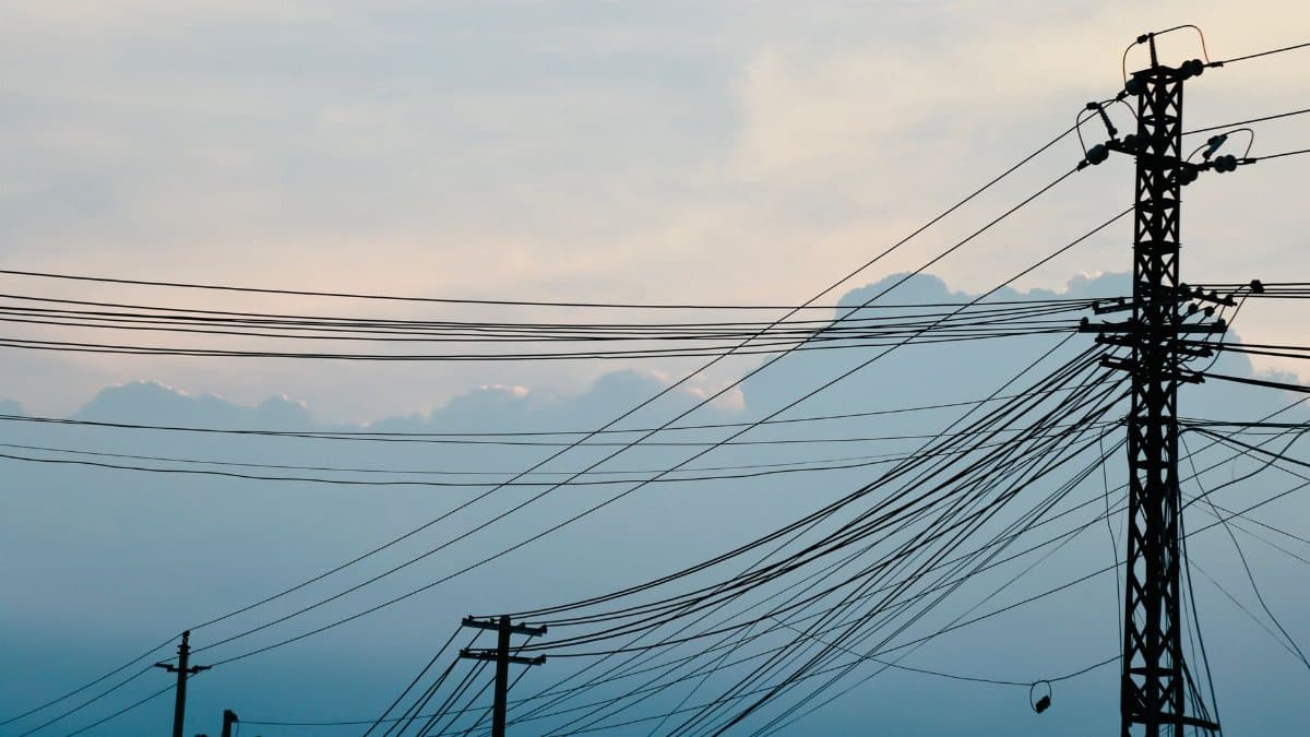 Silhouetted power lines and poles with clouds and sky background, serene atmosphere.