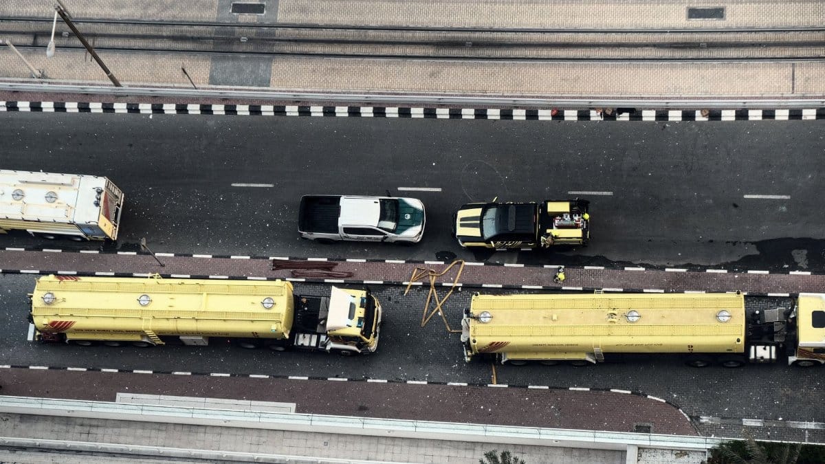 Emergency vehicles respond to a fire incident in a city street, viewed from above.