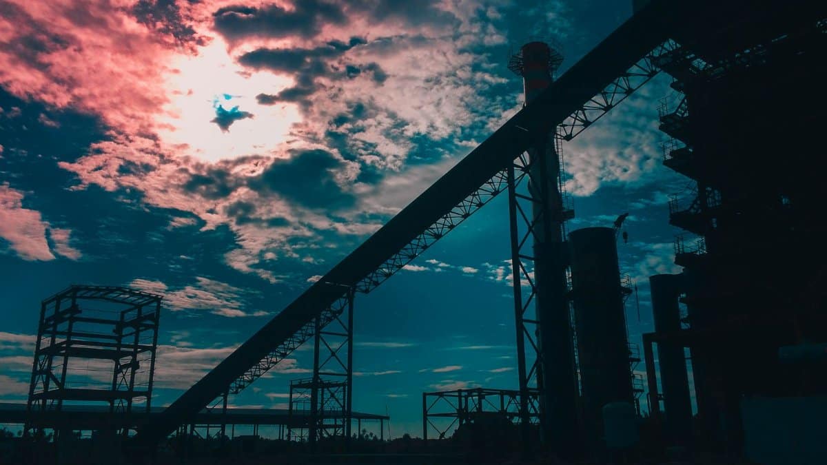 Silhouetted industrial structures at sunset with vibrant clouds in West Kalimantan, Indonesia.