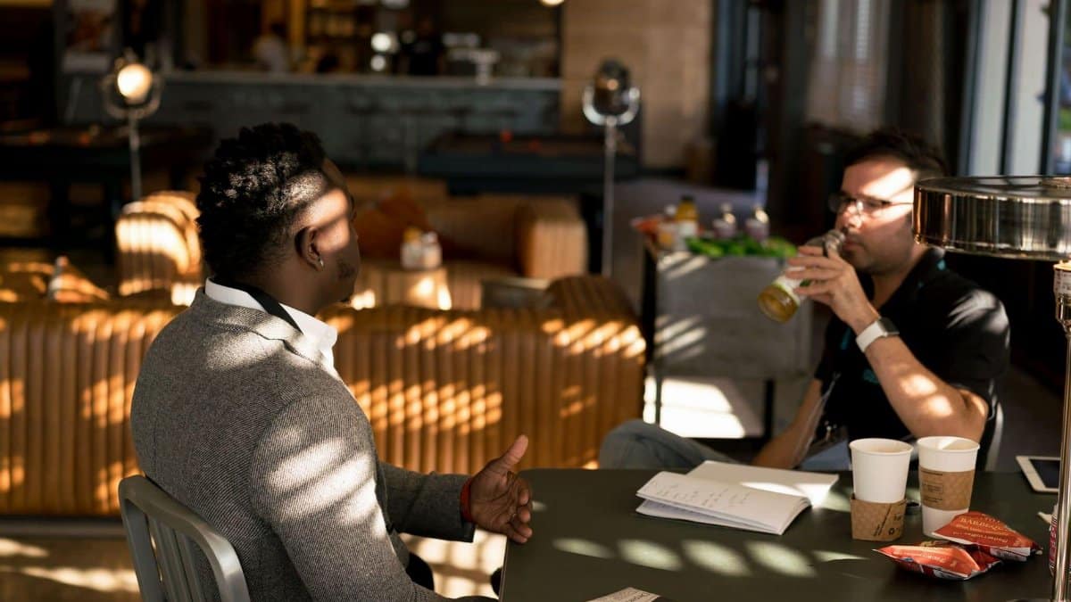 Two adults having a casual meeting with drinks in a modern indoor setting.