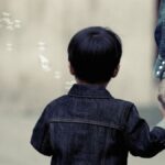 A child and adult walking together holding hands, evoking family bond and care.