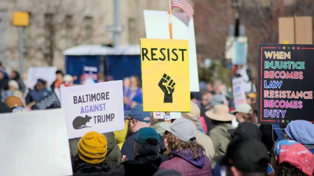 Protesters in Baltimore hold signs advocating resistance and social justice. Location: Baltimore, Maryland.
