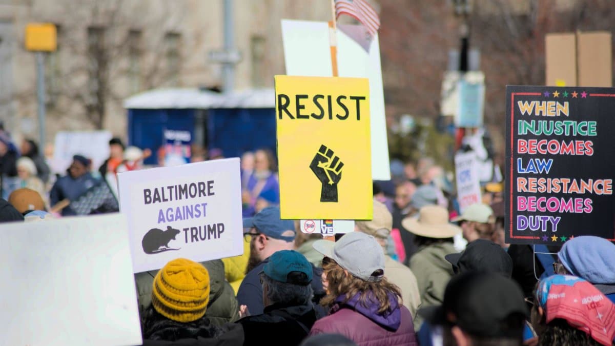 Protesters in Baltimore hold signs advocating resistance and social justice. Location: Baltimore, Maryland.