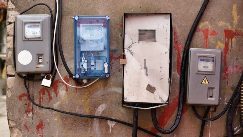 Electrical meters attached to a graffiti-covered wall showcasing utility infrastructure.